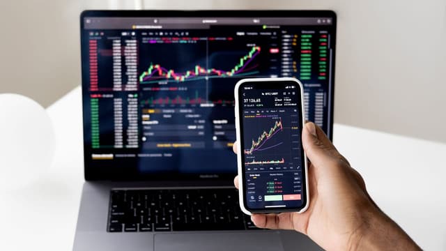 Notebook e celular com gráficos do mercado